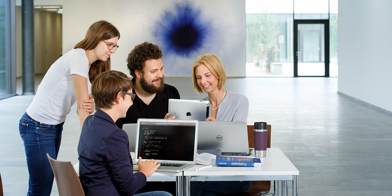 Zentrum für Weiterbildung und Wissensmanagement Vier Studierende sind in einer Lerngruppe mit Laptops und Büchern zusammen gekommen