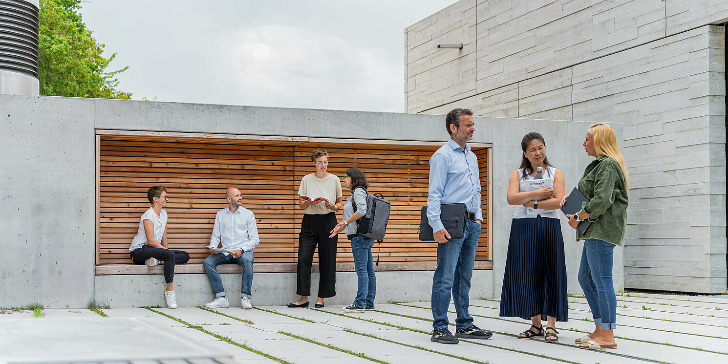 Zentrum für Weiterbildung und Wissensmanagement Studierende unterhalten sich vor einem Seminargebäude in mehreren Gruppen.