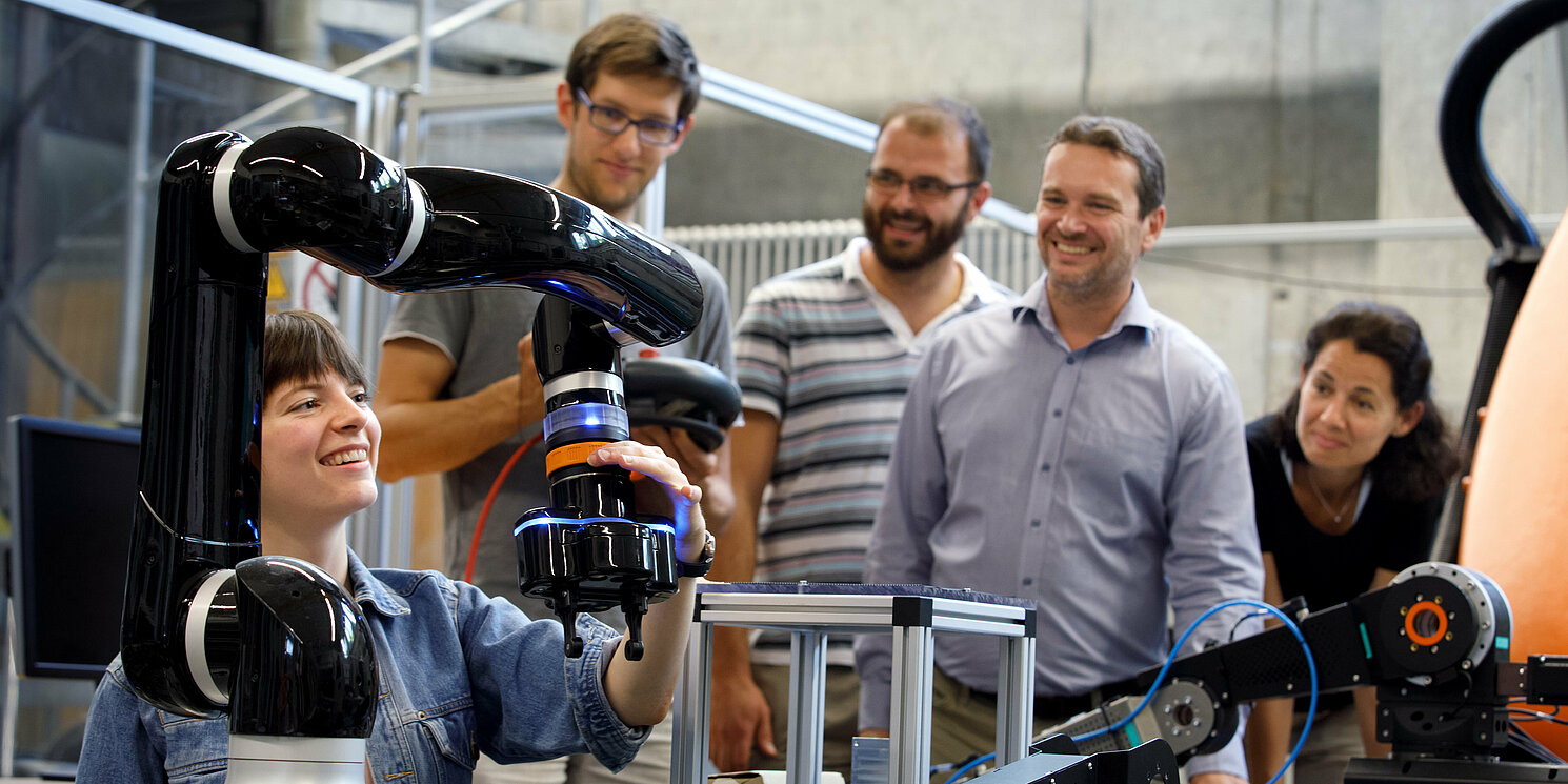 Systemtechnik berufsbegleitend studieren Fünf Studierende arbeiten in einem Labor an technischen Geräten